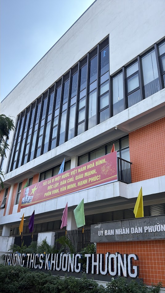 Mặt tiền trường THCS Khương Thượng với băng rôn khẩu hiệu và nhiều cờ màu trước cổng trường